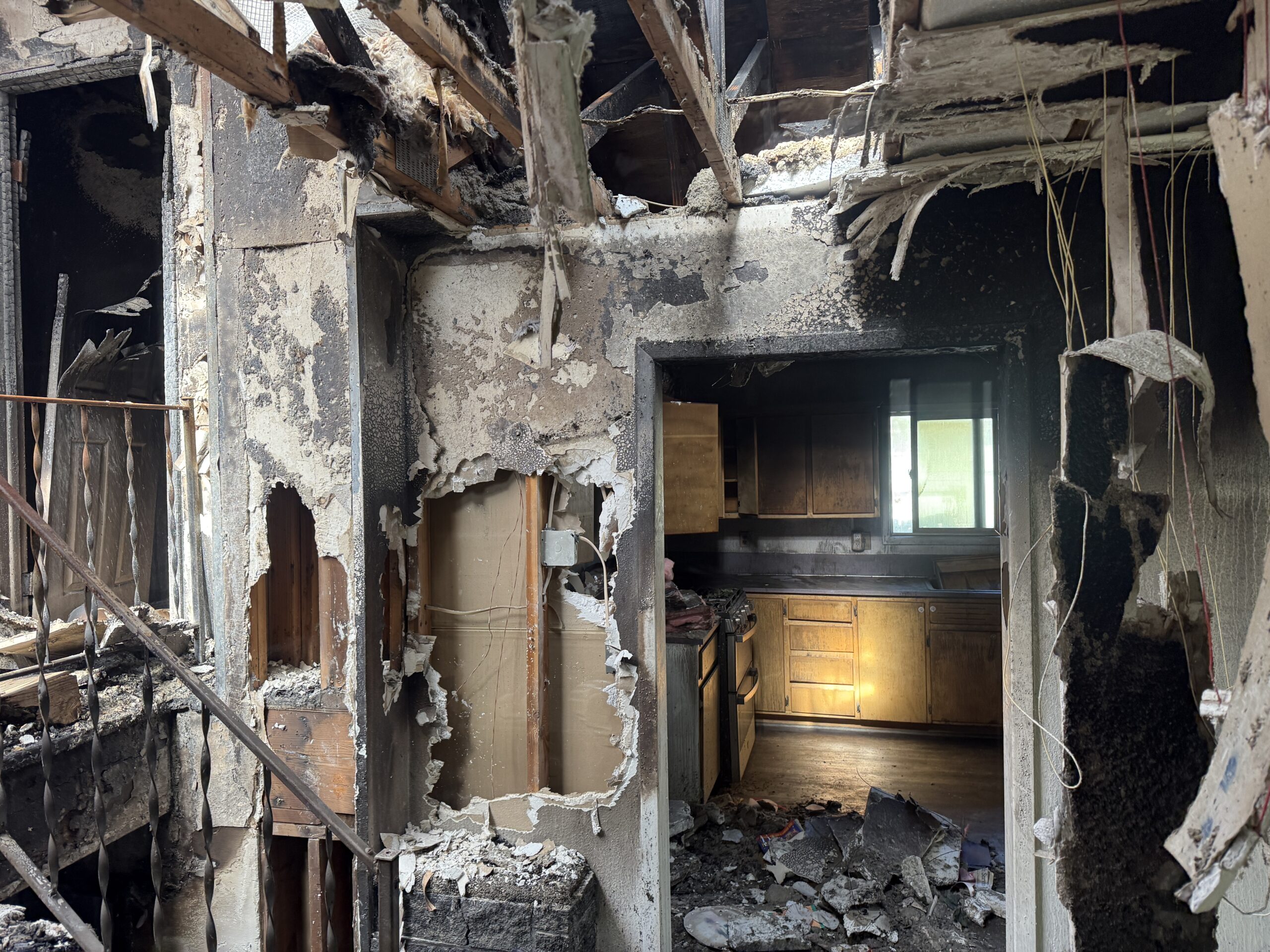Charred framing and burned debris inside a fire-damaged structure