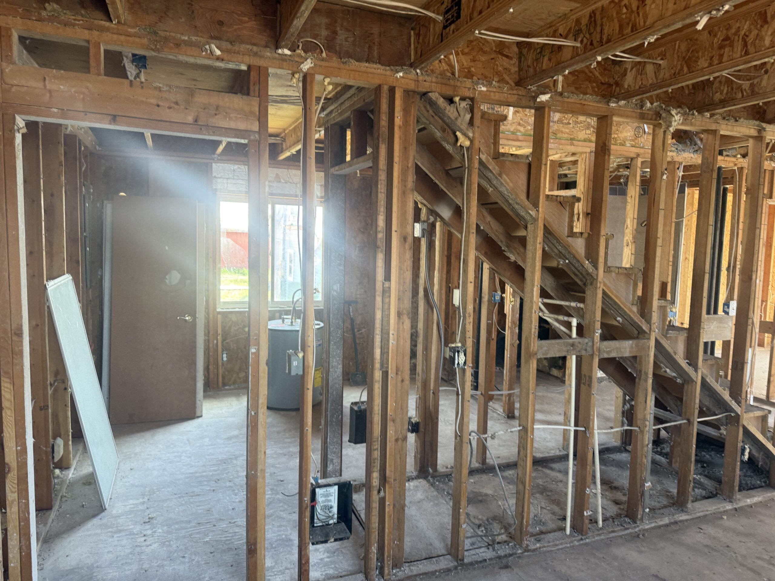 Interior stripped back to framing after fire damage, with daylight through a window