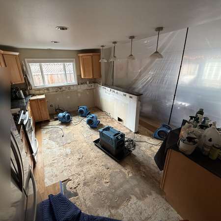 Kitchen stripped during mitigation with drying equipment on the floor