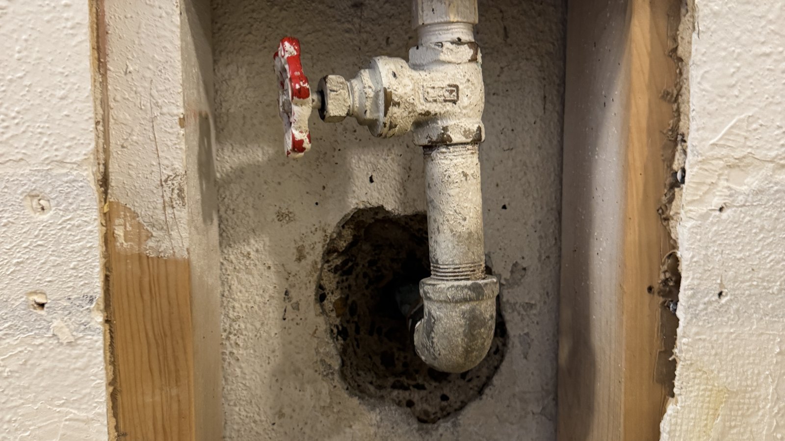 An outdoor faucet pipe exposed inside an opened wall.