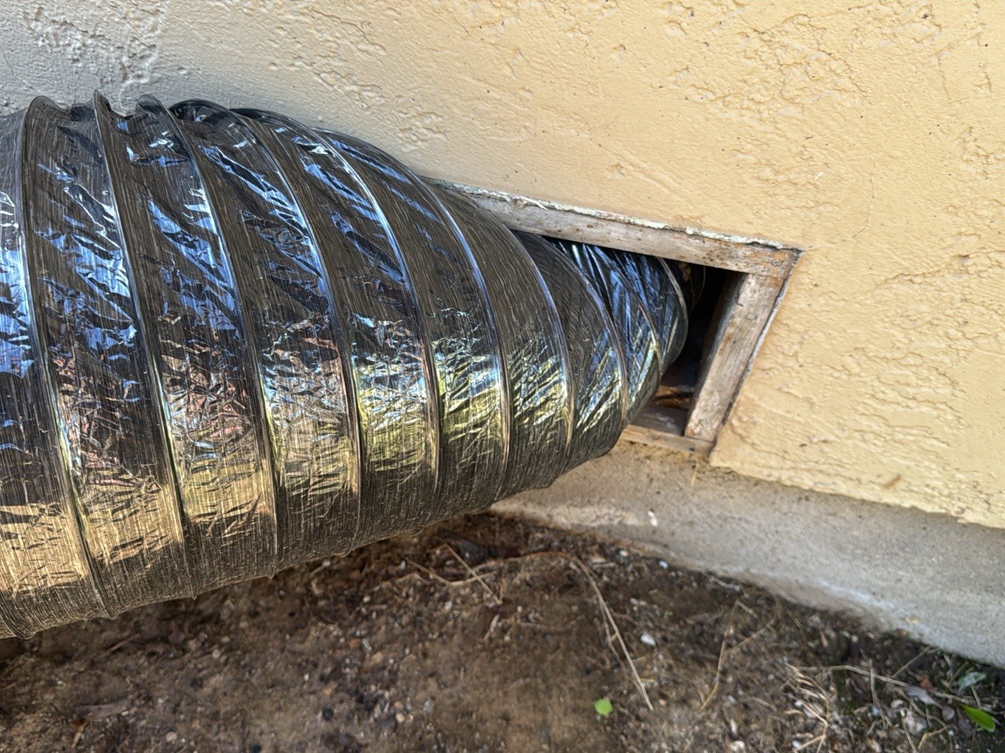 A drying duct running through a foundation vent into a crawl space